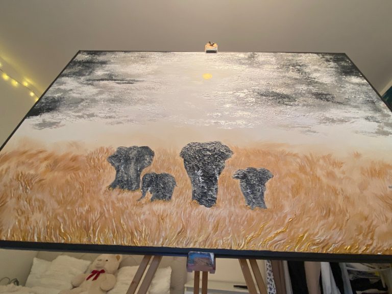Vier Elefanten stehen in einer grasbewachsenen Landschaft unter einem bewölkten Himmel.