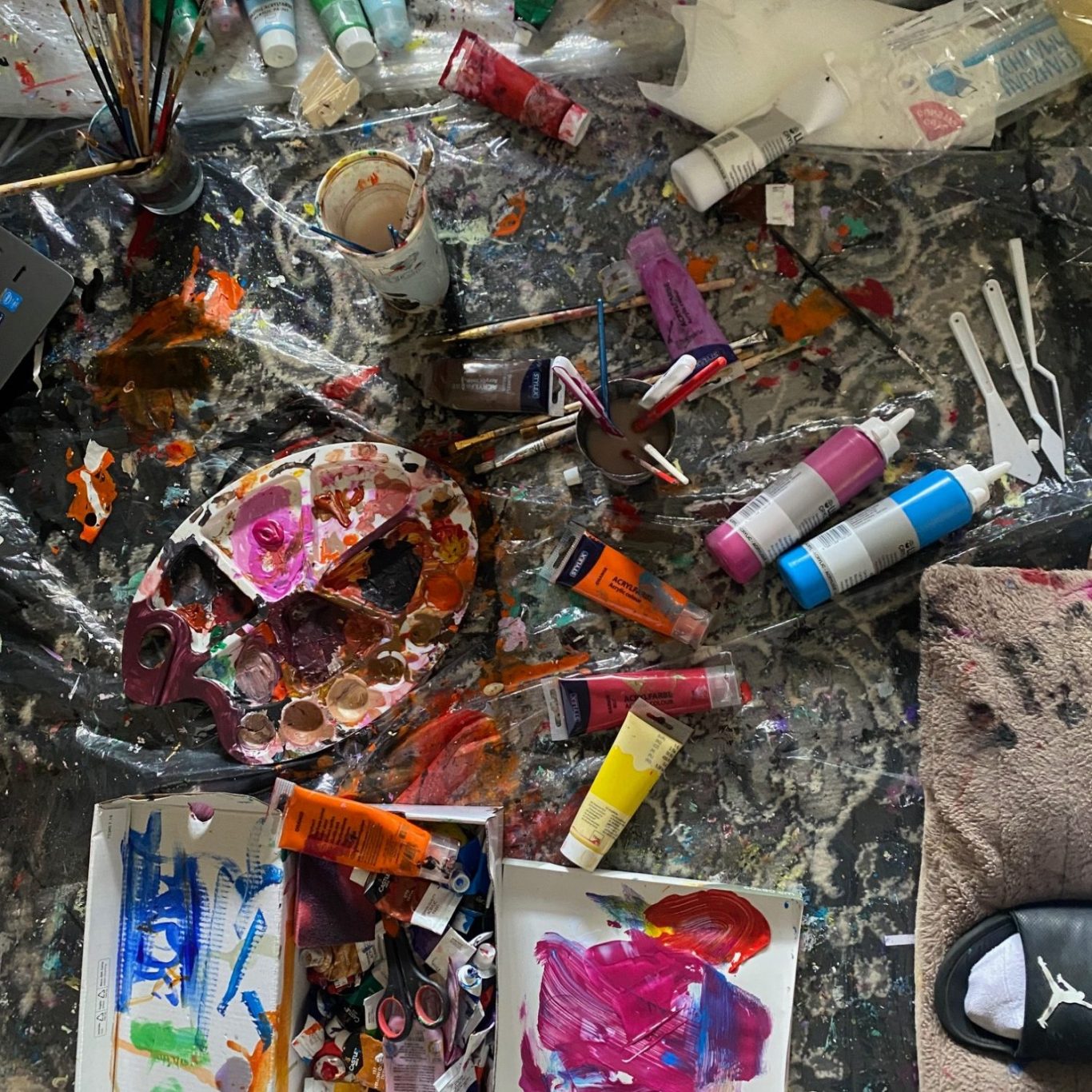 Farben, Pinsel und Malutensilien auf einem unordentlichen Malpalette.
