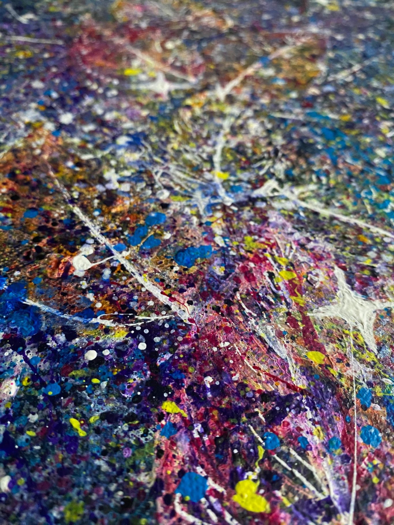 Farbexplosion mit bunten Spritzern in Blau, Lila, Gelb und Weiß auf abstraktem Hintergrund.