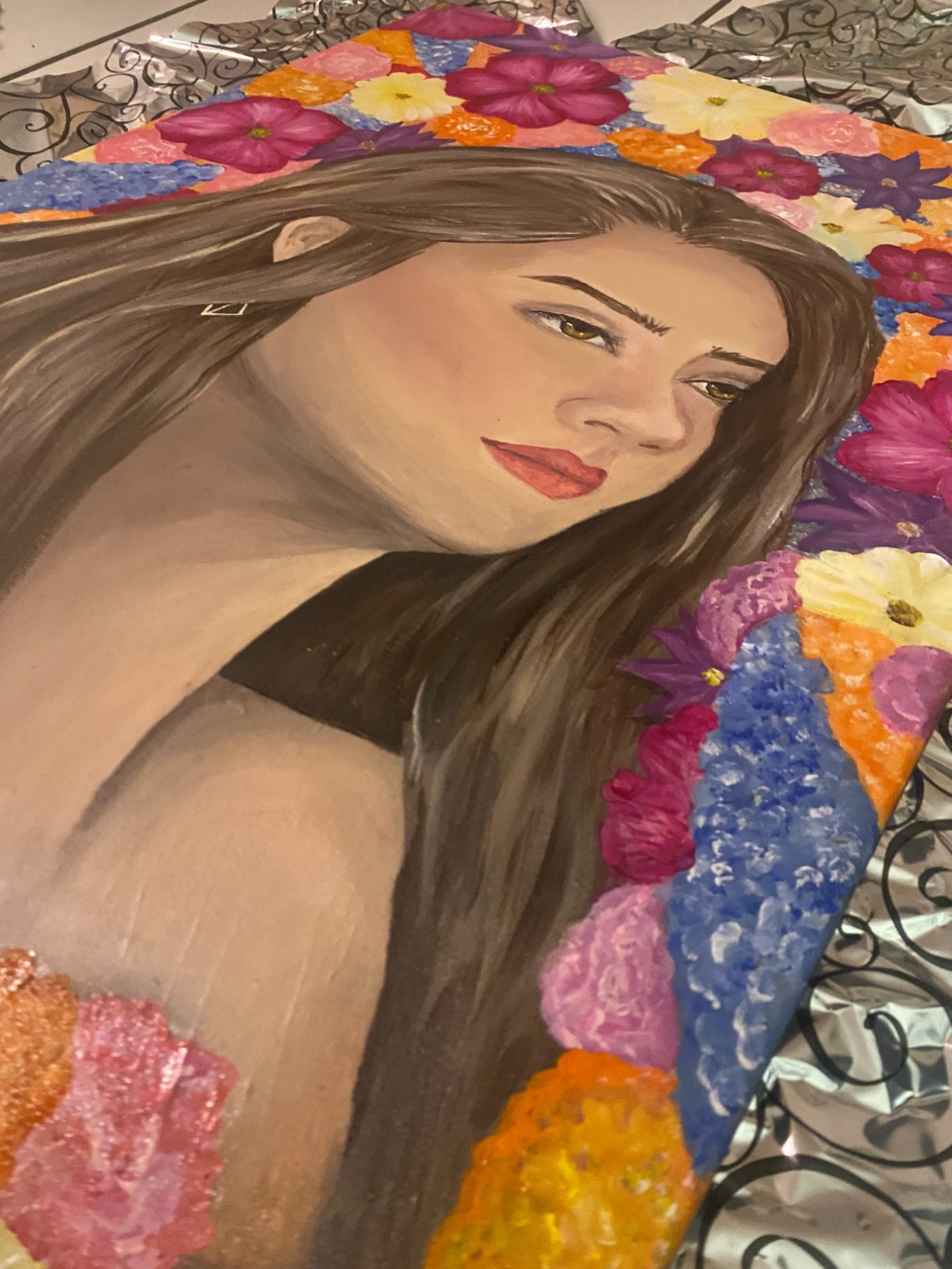 Portrait einer Frau mit langen, braunen Haaren, umgeben von bunten Blumen.