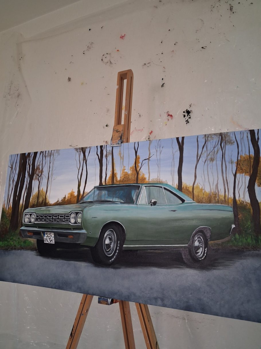 Ein klassisches, grün lackiertes Auto steht vor einer herbstlichen Kulisse.