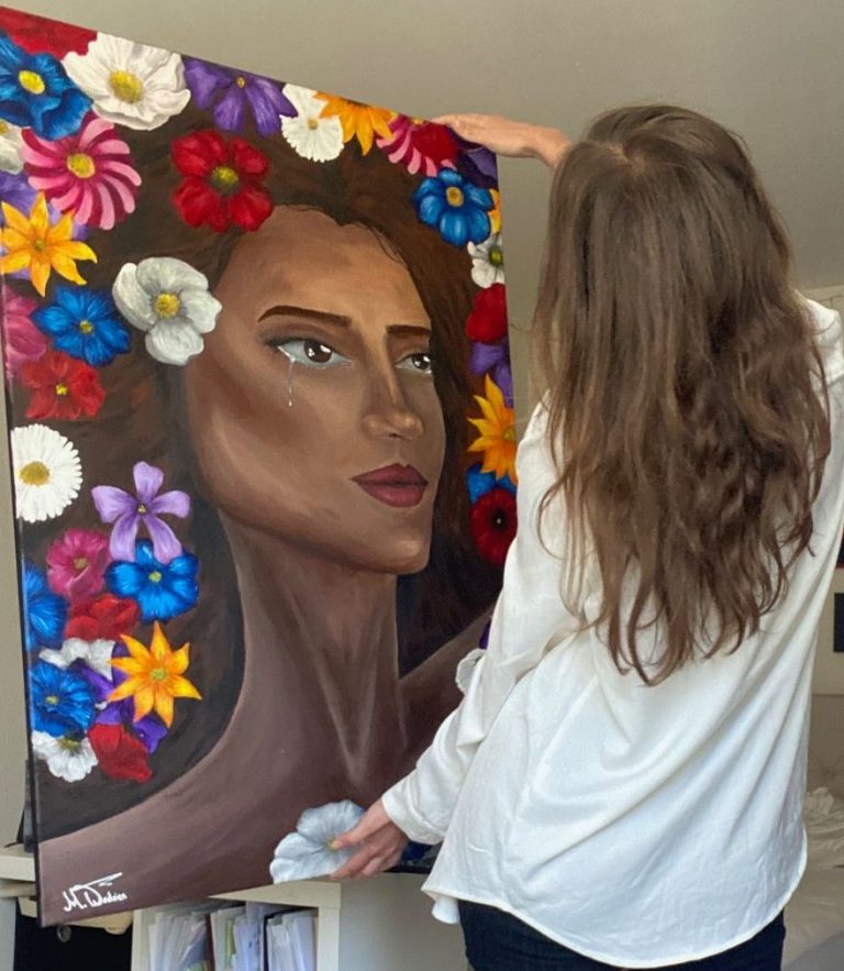 Eine Person hält ein Gemälde einer Frau mit Blumen und lebendigen Farben.