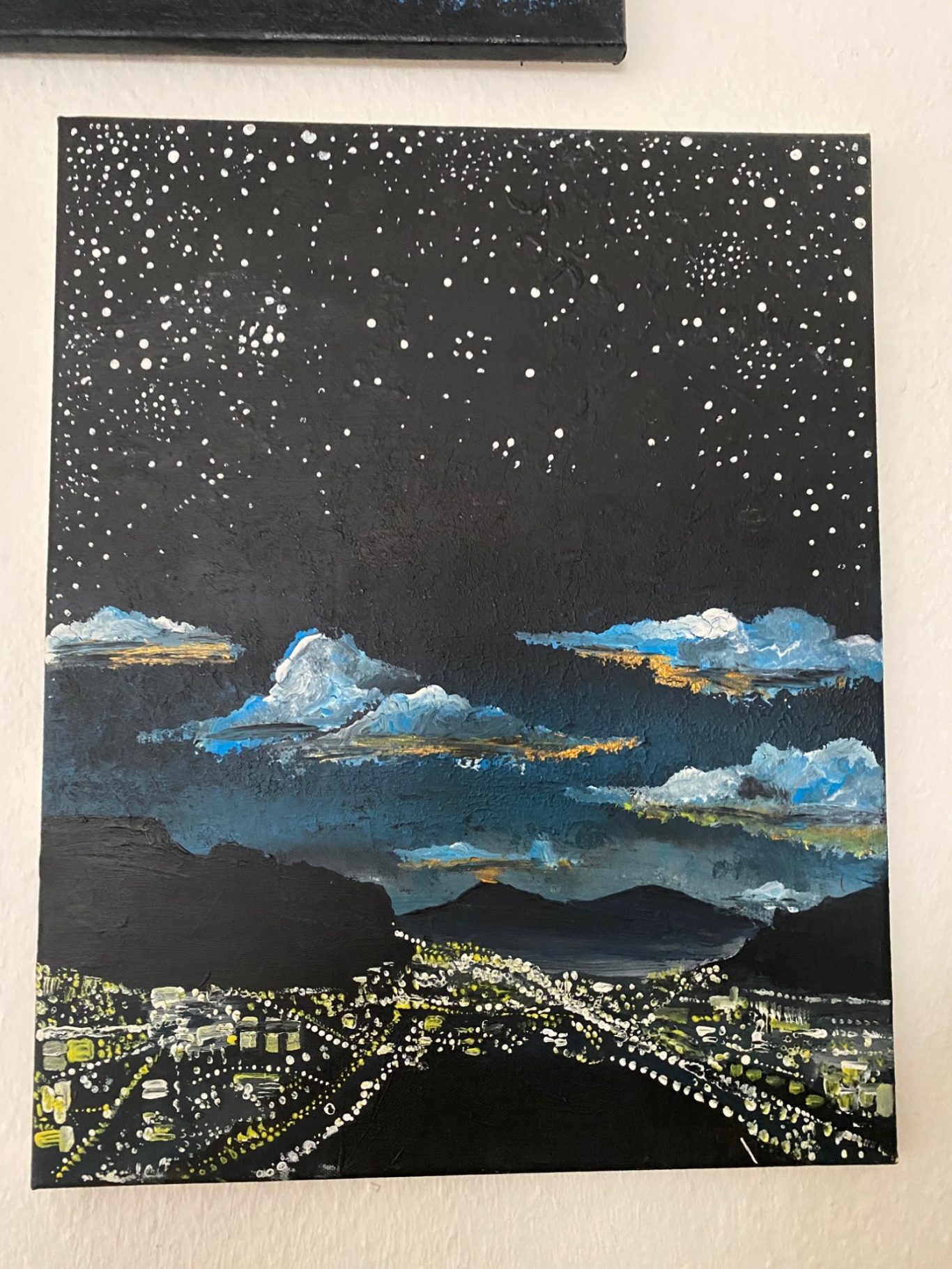 Nachtlandschaft mit Sternenhimmel, Wolken und leuchtenden Lichtern einer Stadt.