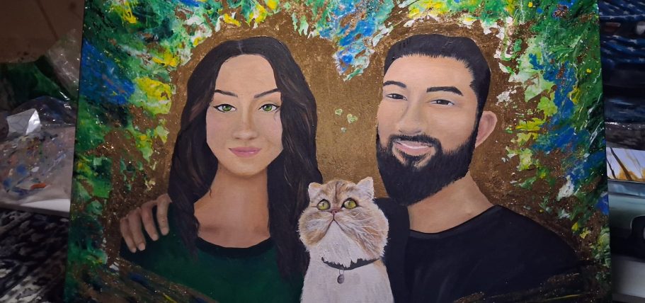 Porträt eines Paares mit einem weißen Kater vor buntem Hintergrund.