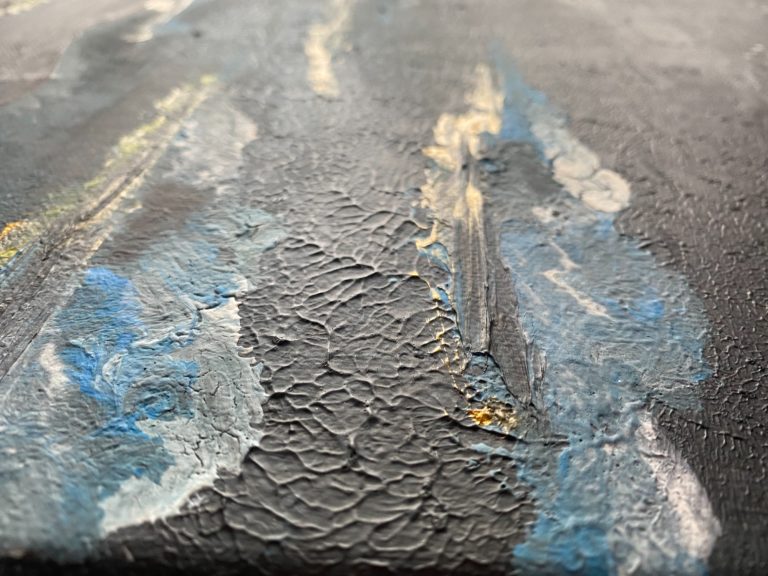 Texturierte Farbflächen in Blau, Schwarz und Gold auf einer dunklen Unterlage.