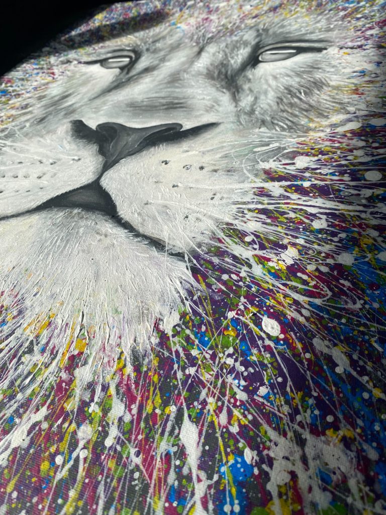 Kunstwerk eines Löwenkopfes mit bunten Farbspritzern im Hintergrund.