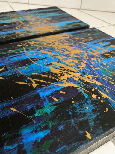 Abstrakte Malerei in Blau und Schwarz mit goldenen Spritzern.