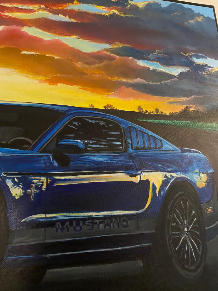 Blaues Sportauto vor einem farbenfrohen Sonnenuntergangshimmel.