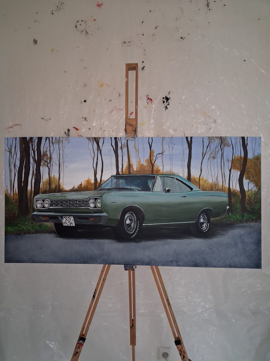 Ein vintage grünes Auto steht auf einer Straße, umgeben von Bäumen und Licht.
